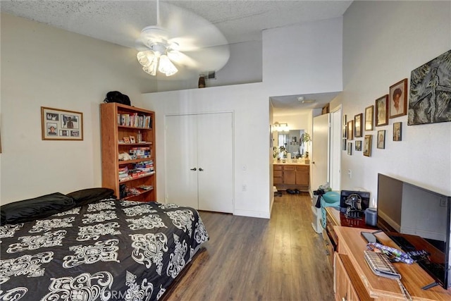 bedroom featuring ensuite bath, ceiling fan, dark wood-type flooring, high vaulted ceiling, and a closet