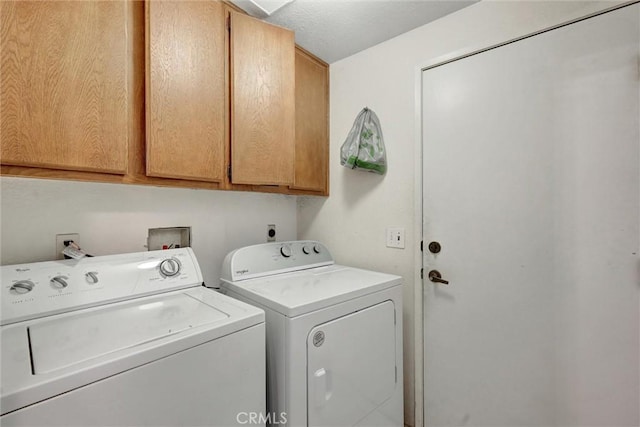 clothes washing area with washer and dryer and cabinets