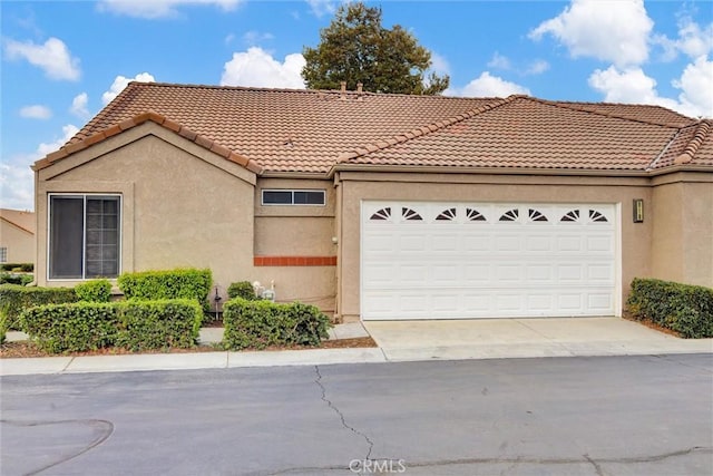 view of front of property with stucco siding, a tiled roof, concrete driveway, and a garage