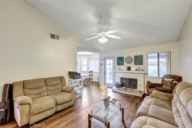 living area with wood finished floors, visible vents, ceiling fan, vaulted ceiling, and a glass covered fireplace