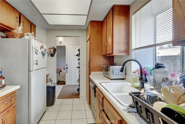 kitchen featuring stainless steel dishwasher, white fridge, light tile patterned flooring, and sink