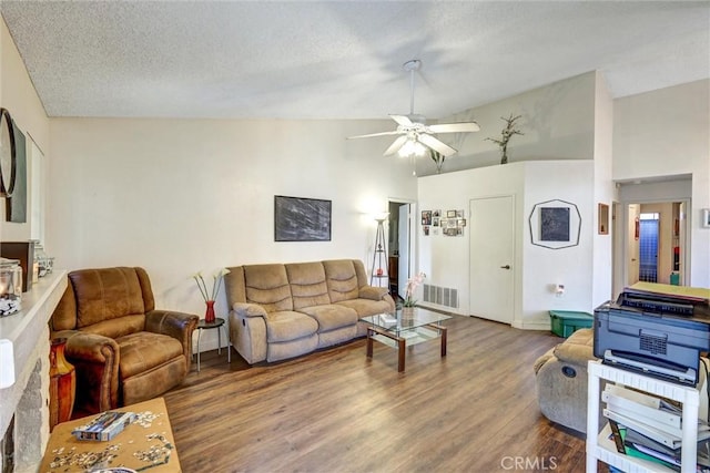 living room with wood finished floors, visible vents, ceiling fan, vaulted ceiling, and a textured ceiling