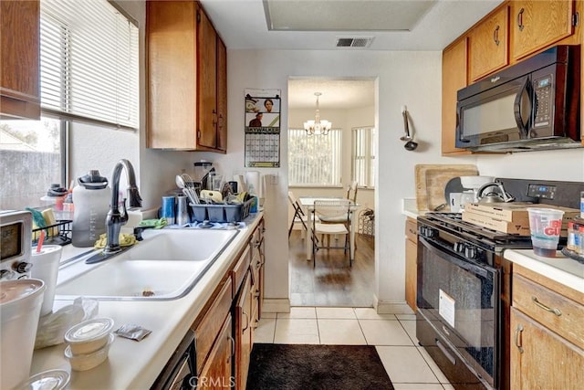 kitchen featuring sink, black appliances, pendant lighting, light tile patterned floors, and a chandelier