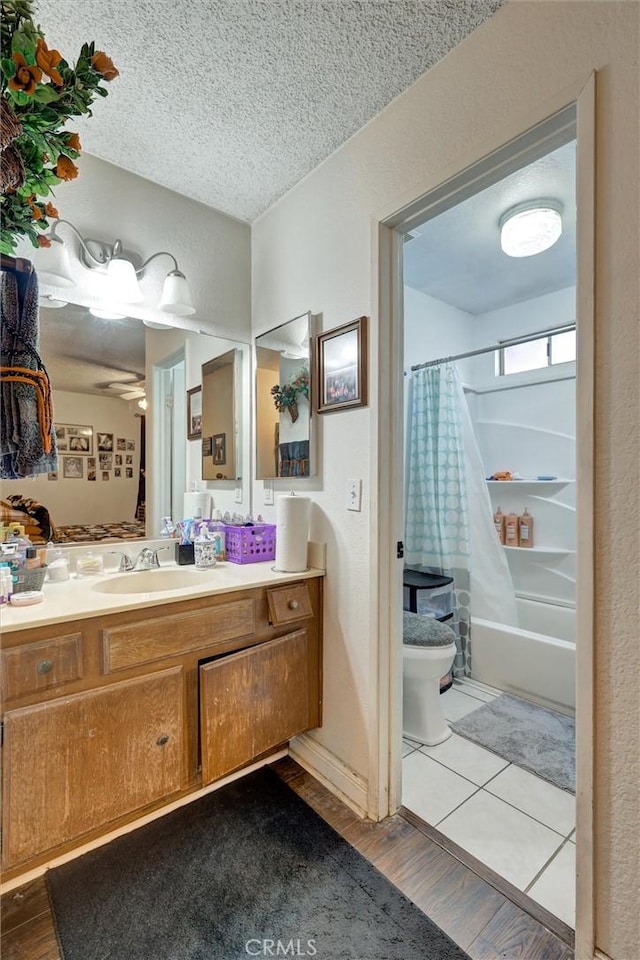 full bathroom with vanity, a textured ceiling, ceiling fan, wood-type flooring, and shower / bathtub combination with curtain