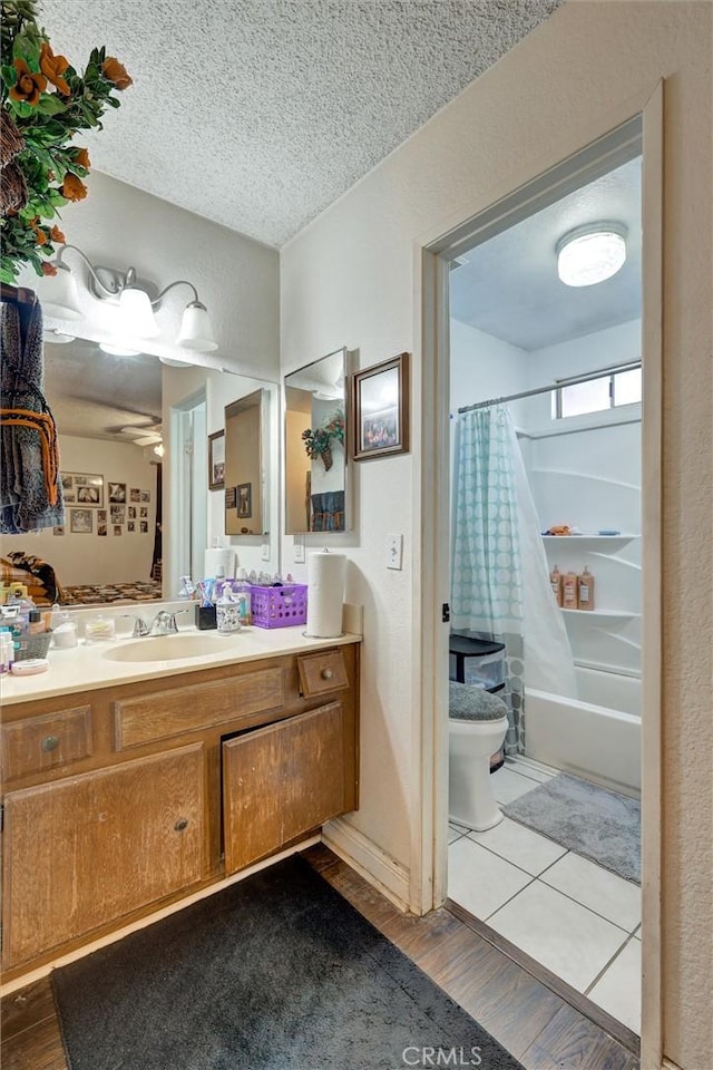full bathroom with toilet, a textured ceiling, wood finished floors, shower / bath combination with curtain, and vanity