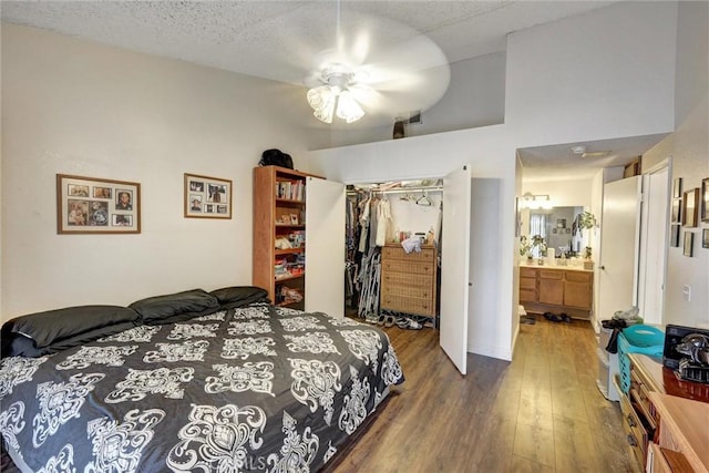 bedroom with a ceiling fan, wood finished floors, ensuite bath, a closet, and a textured ceiling