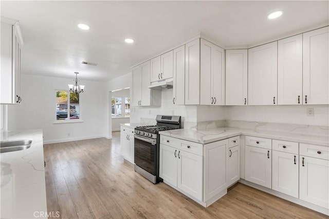 kitchen featuring white cabinets, light wood-type flooring, light stone counters, and stainless steel gas range