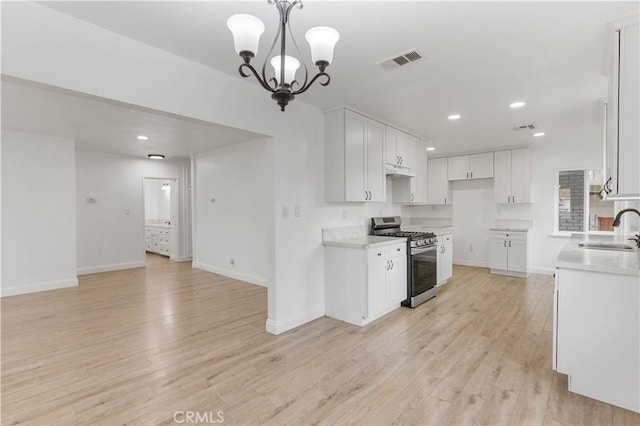 kitchen featuring sink, stainless steel gas range oven, a notable chandelier, white cabinets, and light wood-type flooring