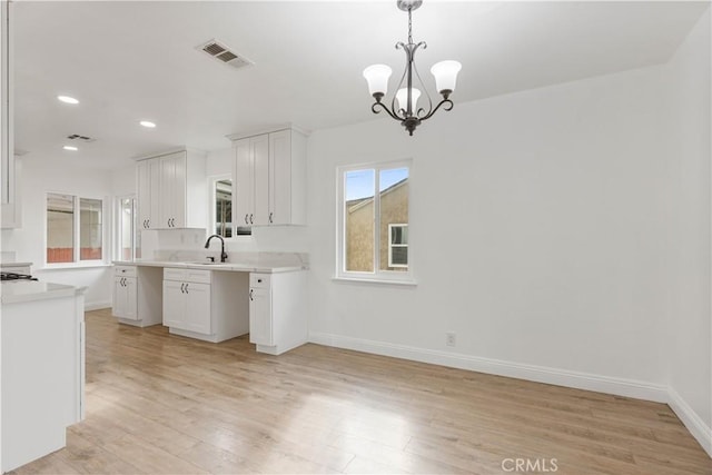 kitchen with a chandelier, sink, white cabinets, and light hardwood / wood-style floors