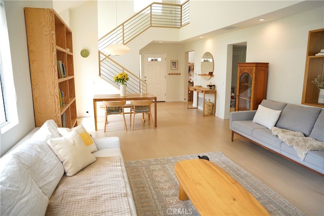 living room featuring a towering ceiling and light hardwood / wood-style floors