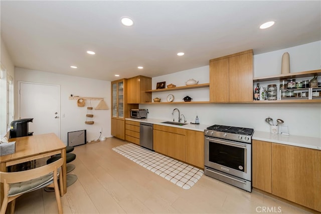 kitchen featuring appliances with stainless steel finishes, sink, and light wood-type flooring