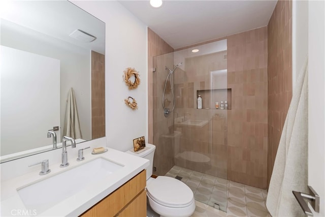 bathroom featuring vanity, toilet, and tiled shower