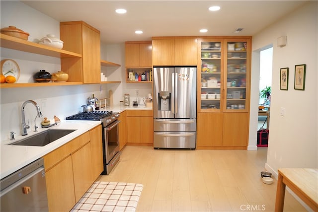 kitchen with appliances with stainless steel finishes, sink, light brown cabinetry, and light hardwood / wood-style floors