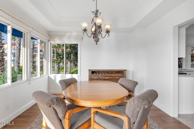 dining area featuring a tray ceiling, dark hardwood / wood-style flooring, and a chandelier