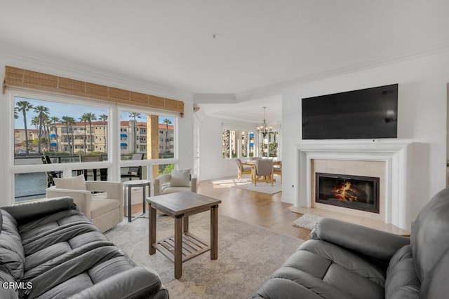 living room with a fireplace, an inviting chandelier, light hardwood / wood-style floors, and ornamental molding