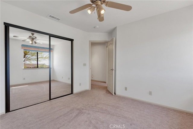 unfurnished bedroom featuring ceiling fan, a closet, and light carpet