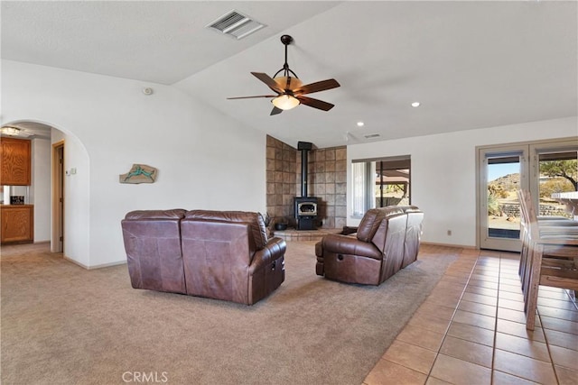 tiled living room with vaulted ceiling, ceiling fan, and a wood stove