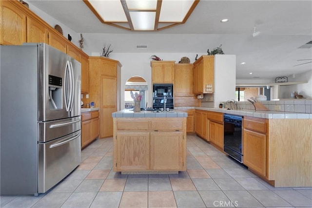 kitchen with tile countertops, kitchen peninsula, light tile patterned flooring, black appliances, and a center island