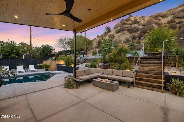 patio terrace at dusk featuring ceiling fan, a fenced in pool, and an outdoor fire pit