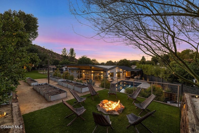 exterior space featuring a fenced in pool, an outdoor fire pit, and a lawn