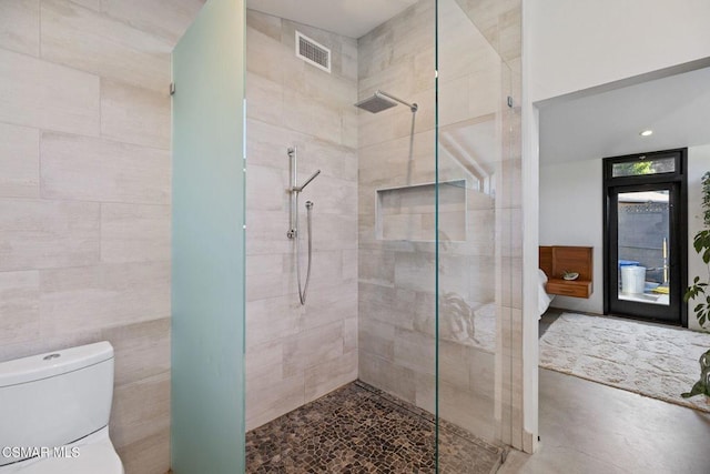 bathroom with a tile shower, concrete floors, tile walls, and toilet