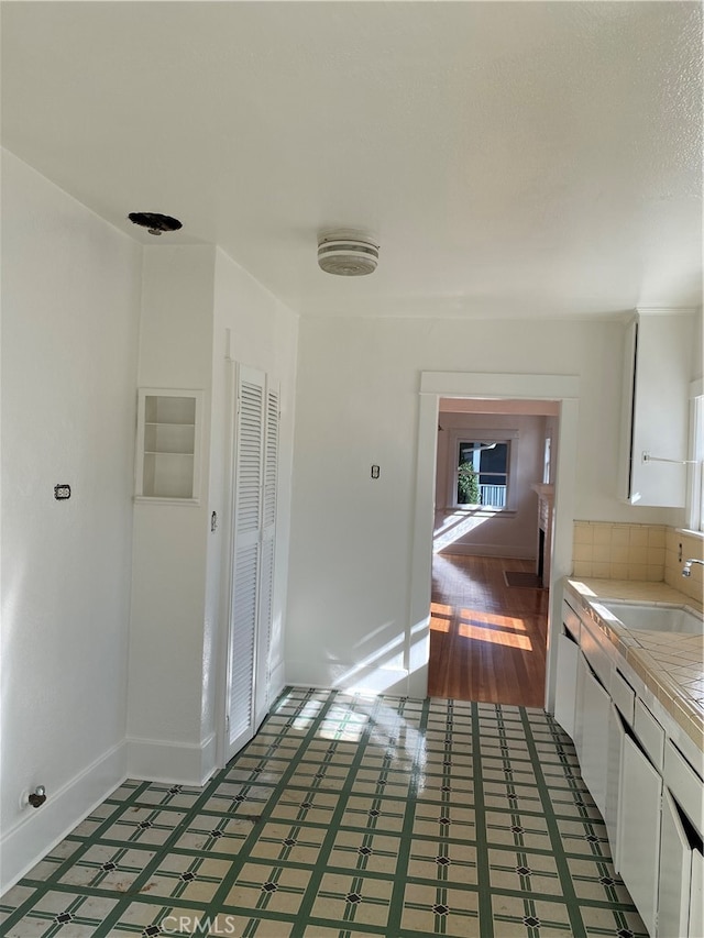 kitchen with hardwood / wood-style floors, sink, white cabinets, and tile counters