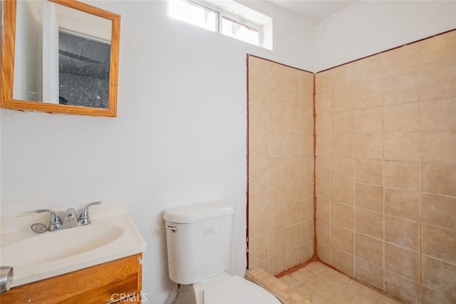 bathroom with toilet, vanity, and tiled shower