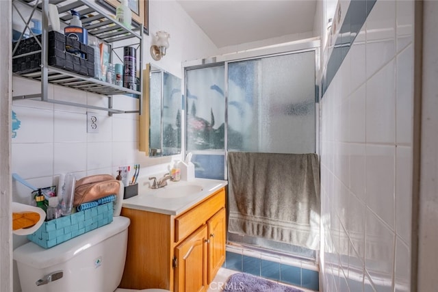 bathroom with vanity, backsplash, tile walls, toilet, and a shower with shower door