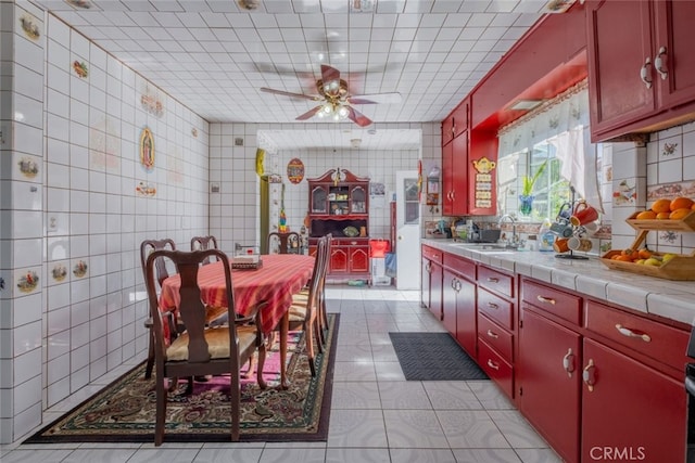 kitchen with tile countertops, tile walls, tasteful backsplash, and sink