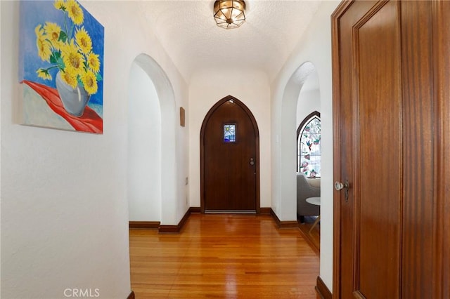 corridor with light hardwood / wood-style floors and a textured ceiling