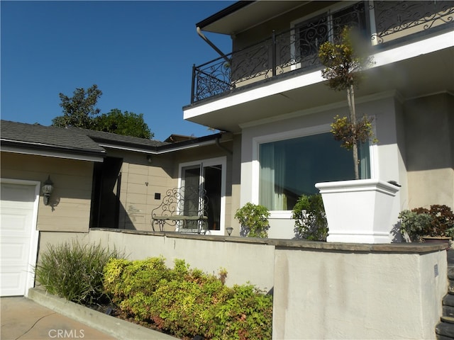 view of side of property featuring a balcony and a garage