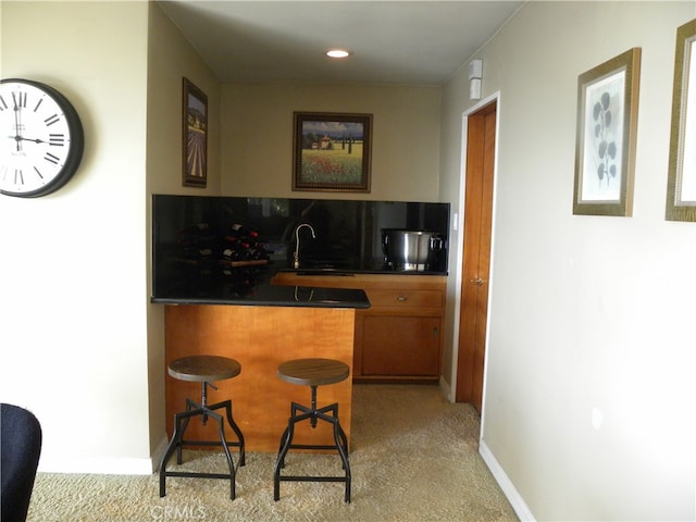 kitchen featuring a breakfast bar, light colored carpet, and sink