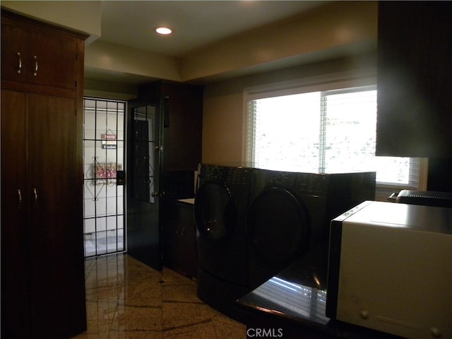 clothes washing area featuring washer and clothes dryer, a healthy amount of sunlight, and cabinets