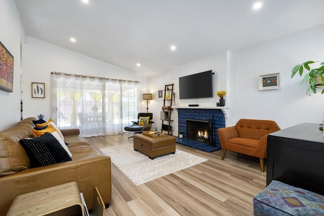 living room with light hardwood / wood-style flooring, lofted ceiling, and a brick fireplace