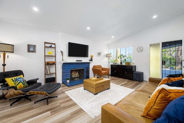 living room with a brick fireplace, light wood-type flooring, and vaulted ceiling