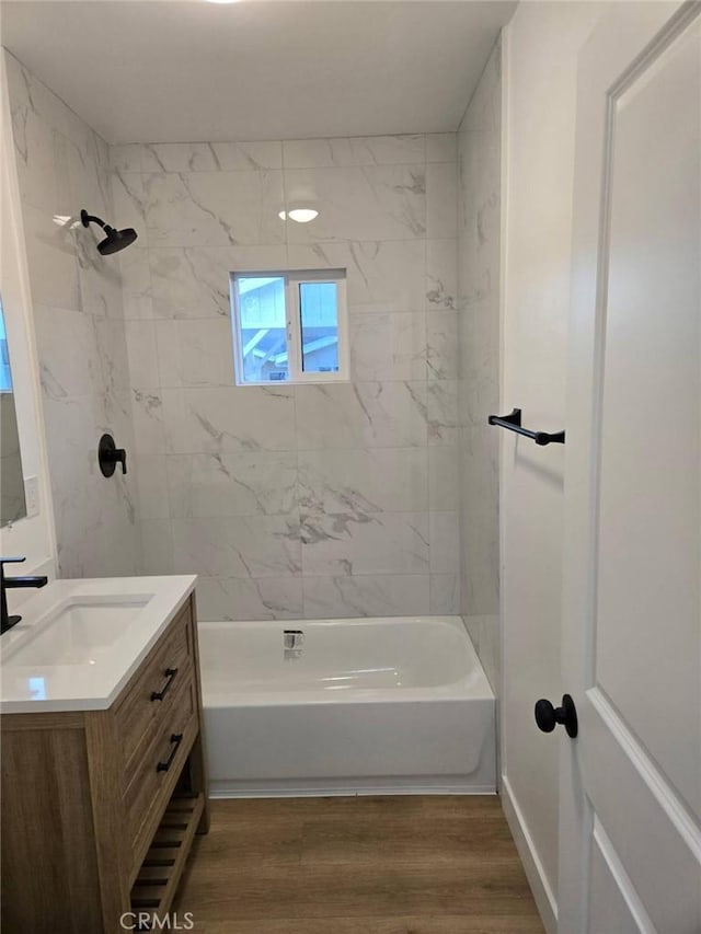 bathroom with wood-type flooring, vanity, and tiled shower / bath