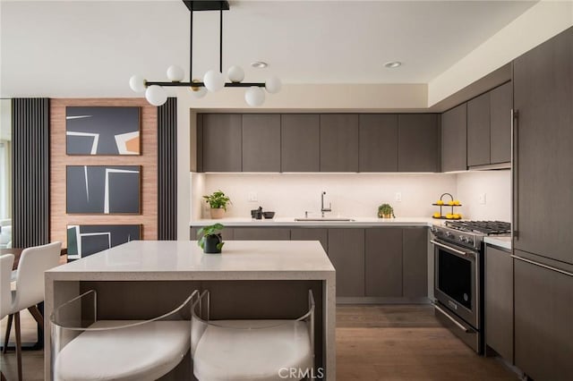 kitchen with hanging light fixtures, sink, high end stainless steel range, dark hardwood / wood-style floors, and a kitchen island