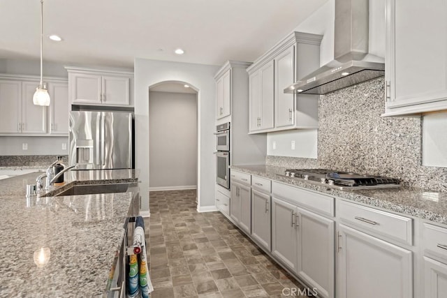 kitchen with white cabinetry, appliances with stainless steel finishes, sink, and wall chimney range hood