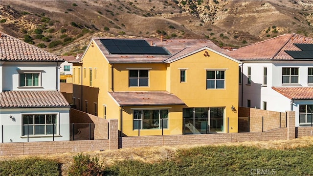 back of house with a mountain view and solar panels