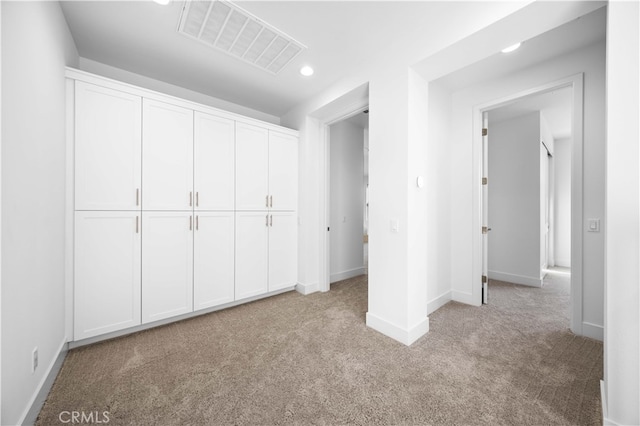 unfurnished bedroom featuring light carpet and a closet