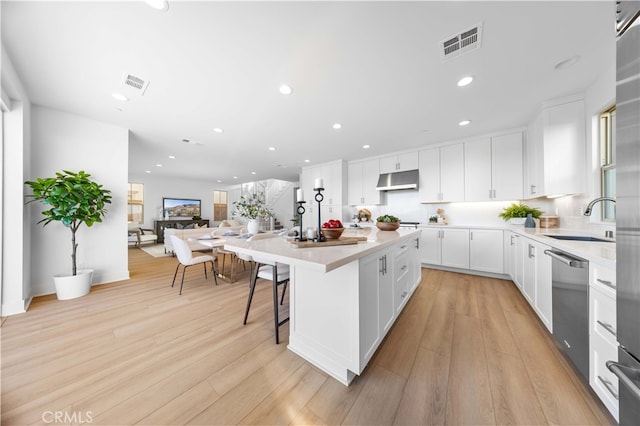 kitchen with light wood-type flooring, a kitchen island, sink, dishwasher, and white cabinetry