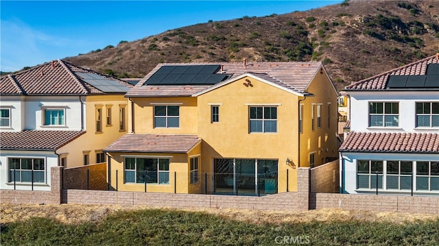 rear view of house with solar panels and a mountain view