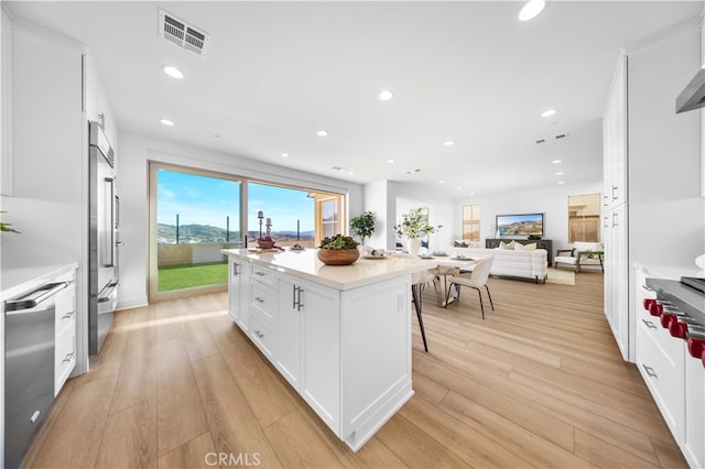 kitchen with white cabinets, a breakfast bar, a kitchen island, and light hardwood / wood-style flooring