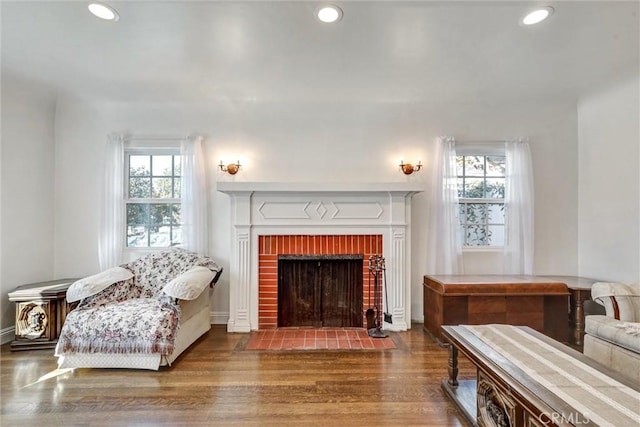 sitting room featuring a wealth of natural light, dark wood-type flooring, and a brick fireplace