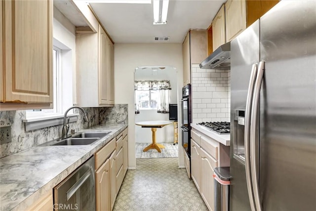 kitchen with decorative backsplash, light brown cabinets, stainless steel appliances, and sink