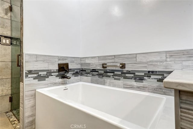 bathroom with a bathing tub, tile patterned flooring, and tile walls