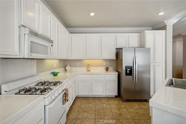 kitchen with white appliances, white cabinets, ornamental molding, light tile patterned floors, and tile counters