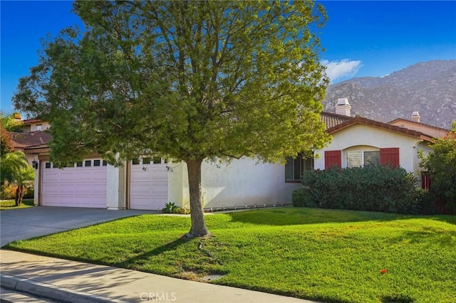 view of property hidden behind natural elements with a mountain view, a garage, and a front yard