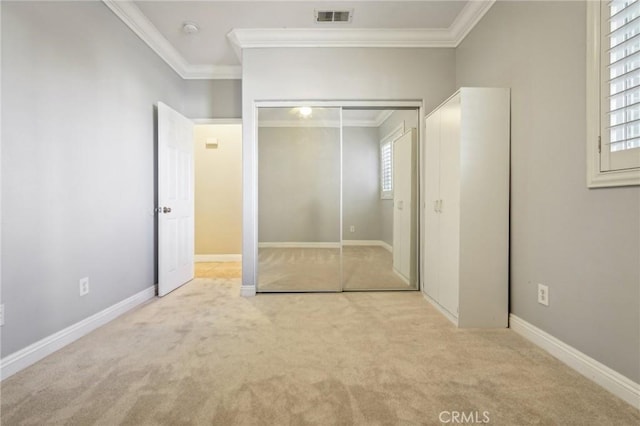 unfurnished bedroom featuring multiple windows, crown molding, a closet, and light colored carpet