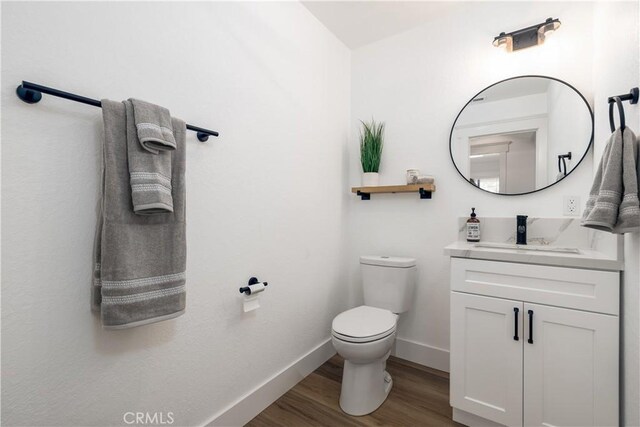 bathroom featuring wood-type flooring, vanity, and toilet